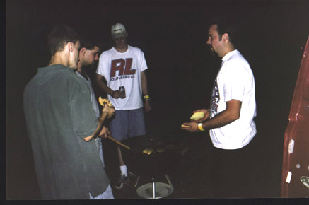 1991 Ford Bronco - People grilling outdoors at night, with a portion of a red vehicle visible.