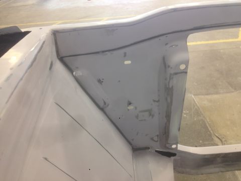 1964 Ford Fairlane - This image shows a section of a car's bodywork, covered in gray primer and showing various seams and mounting holes.