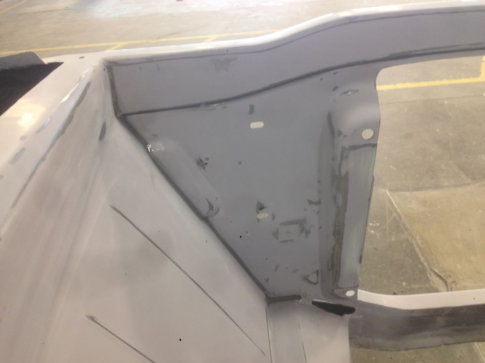 close-up of gray primer on car body panel, showing seams and holes