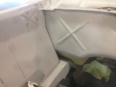 1964 Ford Fairlane - Close-up of a white car's interior, revealing structural details like a cross-shaped reinforcement and ribbed floor.