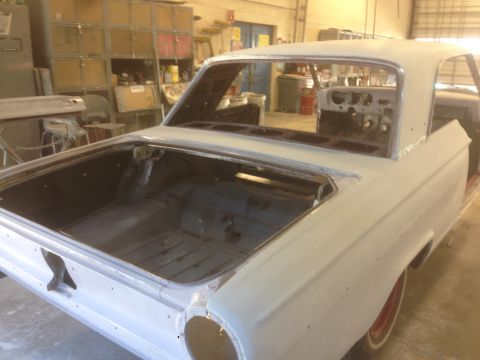 1964 Ford Fairlane - The rear of a 1964 Ford Fairlane is visible in a workshop, showing its open trunk and primer finish.