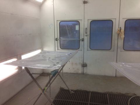 1964 Ford Fairlane - A car hood is prepped for painting inside a professional spray booth.
