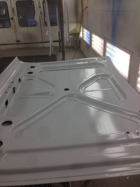 1964 Ford Fairlane - The underside of a car hood is visible inside a paint booth, awaiting further work.