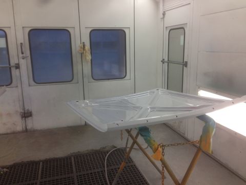 1964 Ford Fairlane - A car hood is prepped for painting in a professional booth.