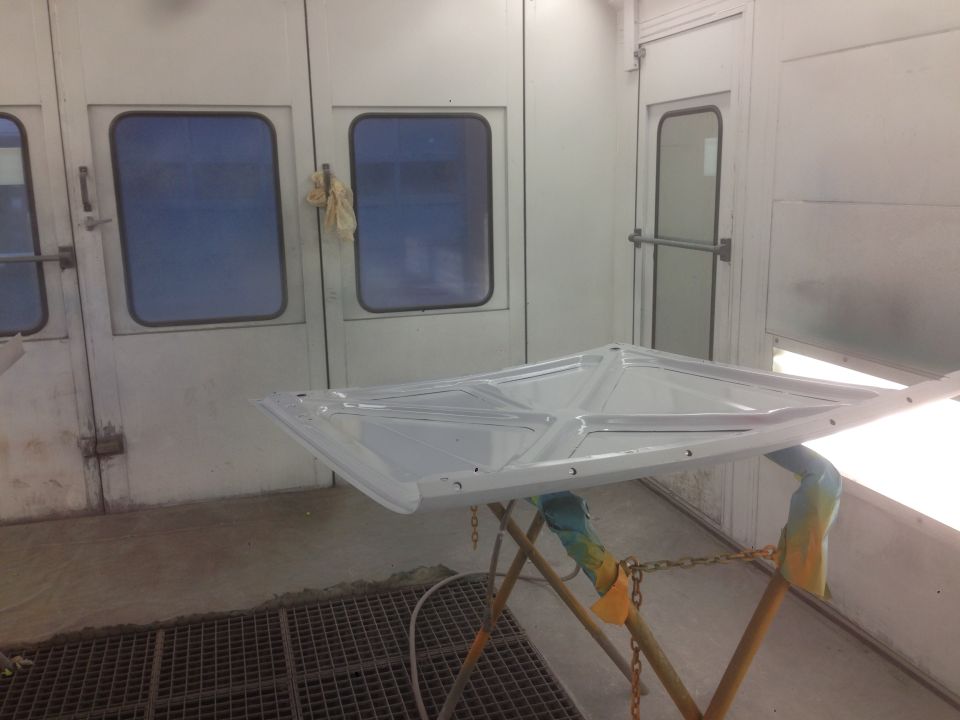 White car hood on a stand inside a paint booth