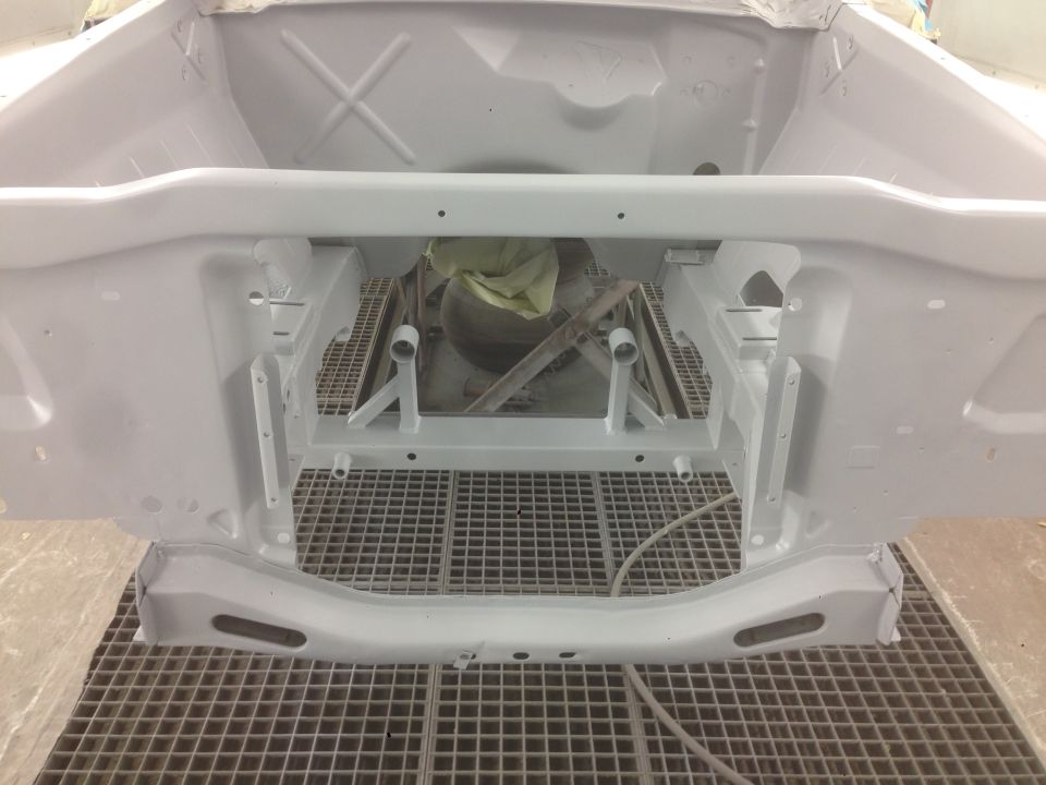 Engine bay frame, primed white, on a grid floor