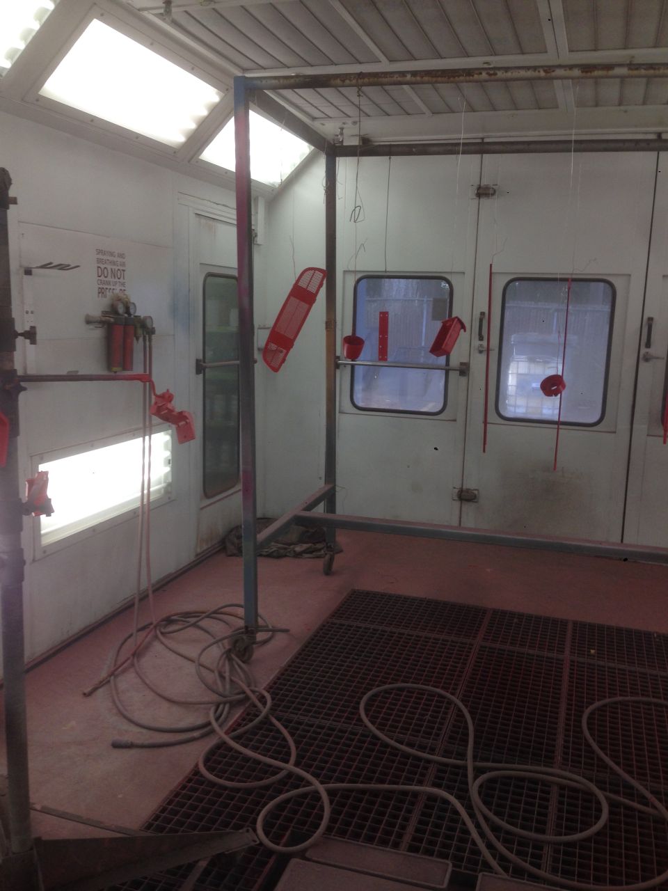 Red car parts hanging in a paint booth