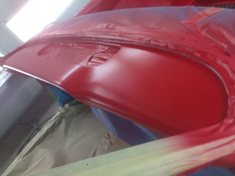 1964 Ford Fairlane - A red car part is being prepped for painting, covered in protective materials.