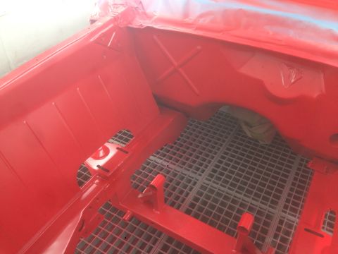 1964 Ford Fairlane - The interior of a red car is visible, with a metal grate on the floor.