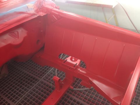 1964 Ford Fairlane - The interior of a red car, likely undergoing restoration, reveals freshly painted chassis and firewall components.
