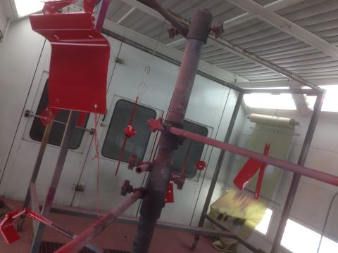 1964 Ford Fairlane - Car parts being painted red inside a professional spray booth.