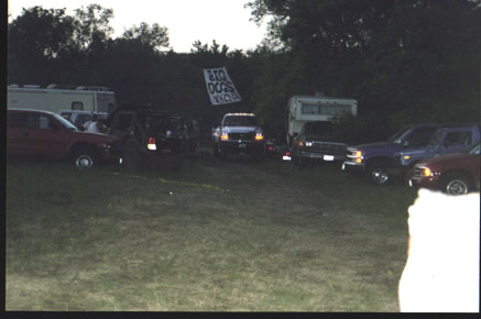 1991 Ford Bronco - A collection of vehicles are parked together in an outdoor setting, with a banner hanging in the background.