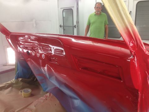 1964 Ford Fairlane - A man watches as a car's dashboard is being painted red inside a spray booth.