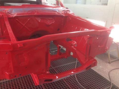 1964 Ford Fairlane - The front frame of a red 1964 Ford Fairlane is visible, freshly painted and ready for assembly.