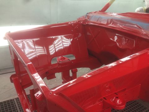 1964 Ford Fairlane - Car frame receives a fresh coat of red paint inside a professional paint booth.