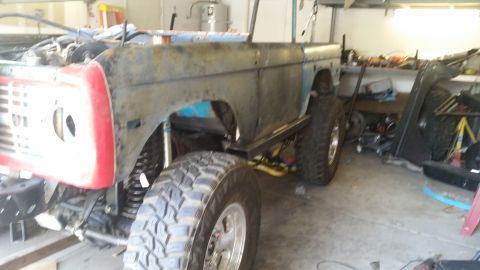 1979 Ford Bronco - A partially restored 1978 Ford Bronco sits in a garage, showing significant rust and custom modifications.