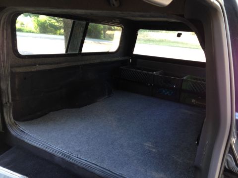2001 Ford Ranger - View inside a truck bed, equipped with a camper shell and carpeted floor, plastic storage crates.