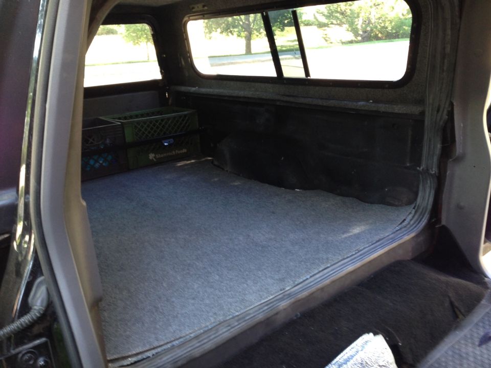 Interior view of a pickup truck bed with carpet and two milk crates