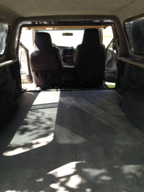 2001 Ford Ranger - The interior of a pickup truck shows the seats and dashboard, with the truck bed covered in protective mats.