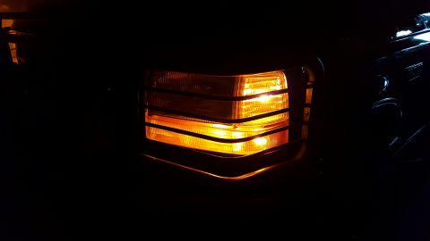 1996 Ford Bronco - The amber turn signal light on the front corner of a vehicle is illuminated in the dark.
