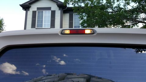 1996 Ford Bronco - Close-up of a white third brake light assembly with red and amber lenses, mounted above a tinted rear window.