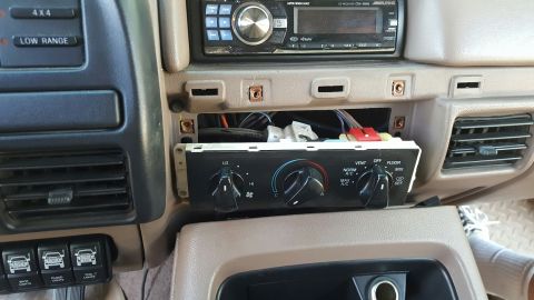 1996 Ford Bronco - The dashboard of a car shows exposed wiring and climate controls removed from the dash panel.