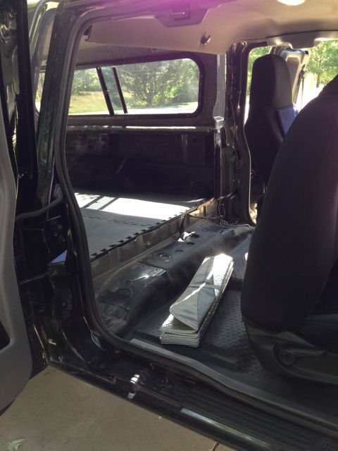 2001 Ford Ranger - The interior of a truck bed is shown, seats and a folded mat on the floor.