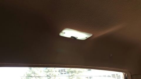 1996 Ford Bronco - Interior dome light on brown headliner, with a glimpse of the exterior through the window.