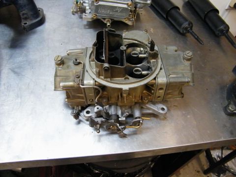 1967 Mercury Cougar - A Holley carburetor sits on a workbench, possibly awaiting installation or repair.