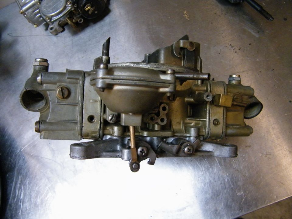 Holley carburetor on a metal surface. Another carburetor is partially visible in the background