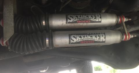1995 Ford Bronco - Underside view of two Skyjacker 9000 suspension shocks with black bellows, attached to a vehicle.