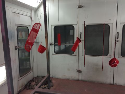 1964 Ford Fairlane - Car parts are suspended and drying after being painted red in a spray booth.