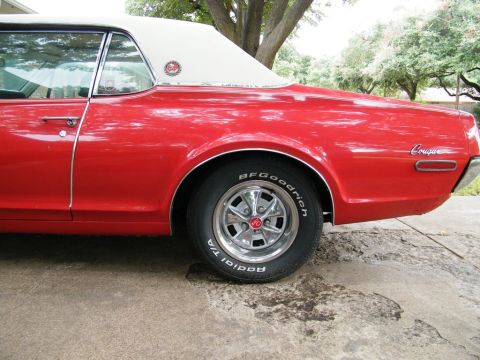 1968 Mercury Cougar - The rear quarter panel and wheel of a red 1968 Mercury Cougar are visible.