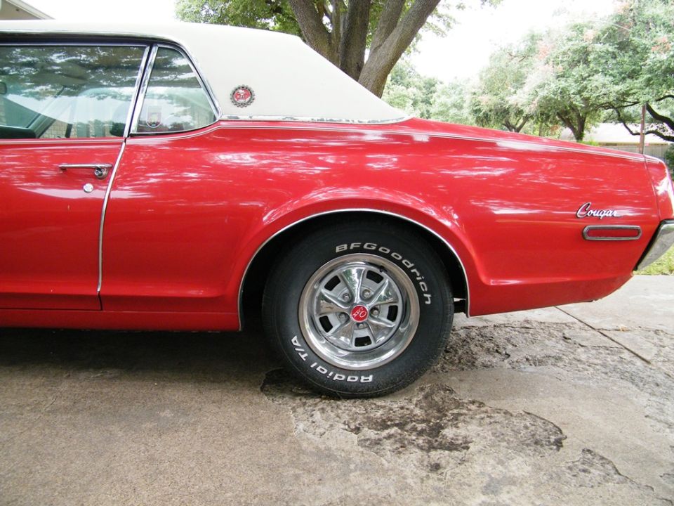 red 1968 Mercury Cougar with white vinyl top, side view