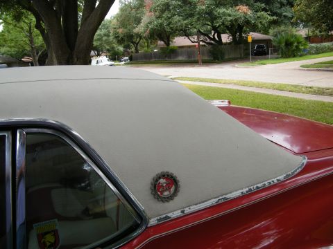 1968 Mercury Cougar - The vinyl top of a red car is visible, with a decorative emblem on the rear pillar.