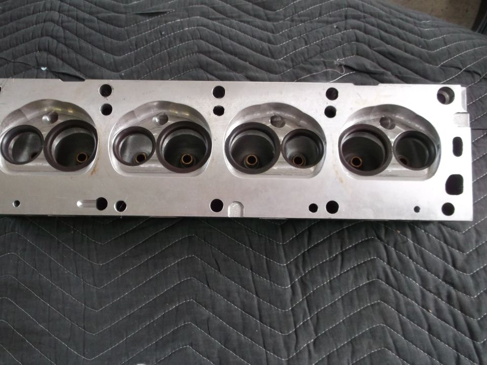 Close-up of an aluminum engine cylinder head with four pairs of intake and exhaust ports