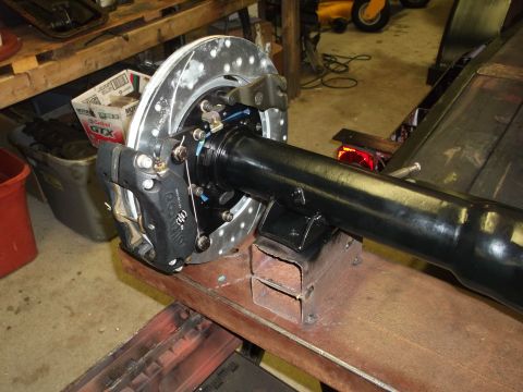 1967 Ford Mustang - Close-up view of a vehicle's rear axle and brake system, undergoing maintenance or modification.