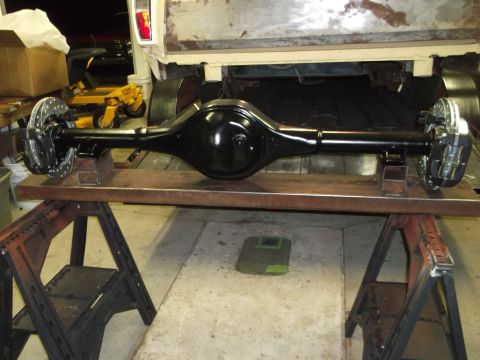 1967 Ford Mustang - A black rear axle assembly with disc brakes is displayed on sawhorses, with the rear of a white truck in the background.