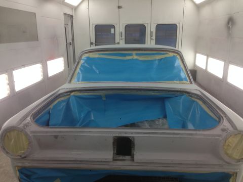 1964 Ford Fairlane - A car is prepped for painting inside a brightly lit booth, with its trunk open and covered.
