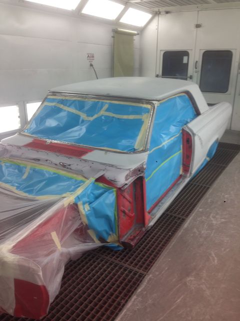 1964 Ford Fairlane - A 1964 Ford Fairlane is prepped for painting inside a professional booth, with windows and body panels covered in blue masking.