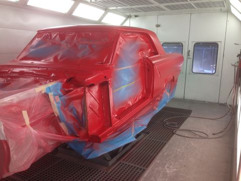 1964 Ford Fairlane - A 1964 Ford Fairlane body is being painted red inside a professional paint booth.