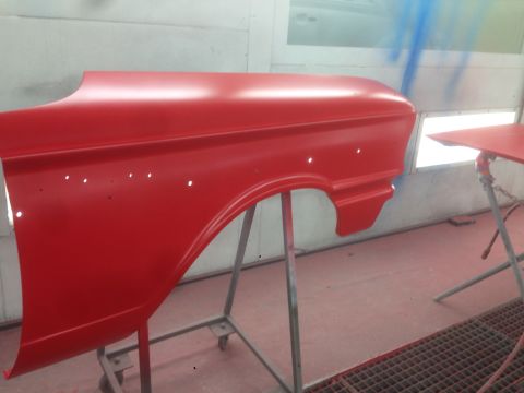 1964 Ford Fairlane - A red car fender is prepped for painting in a booth.