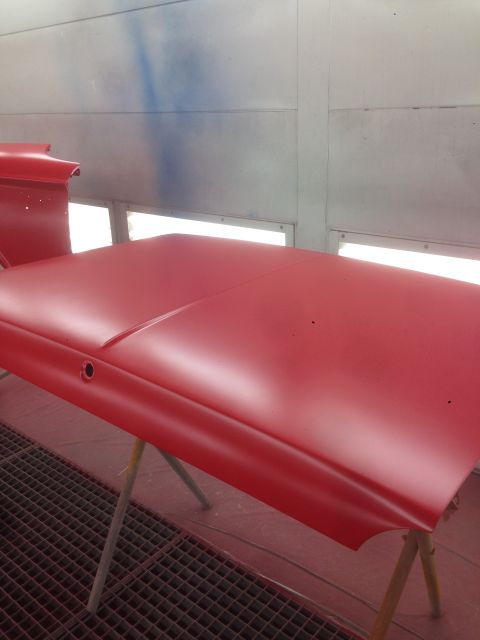 1964 Ford Fairlane - A red car hood is being prepped for painting inside a spray booth.