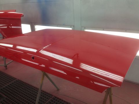 1964 Ford Fairlane - A freshly painted red car hood is shown in a paint booth, awaiting reassembly.