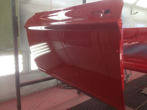 1964 Ford Fairlane - A freshly painted red car door is suspended in a spray booth, awaiting reassembly.