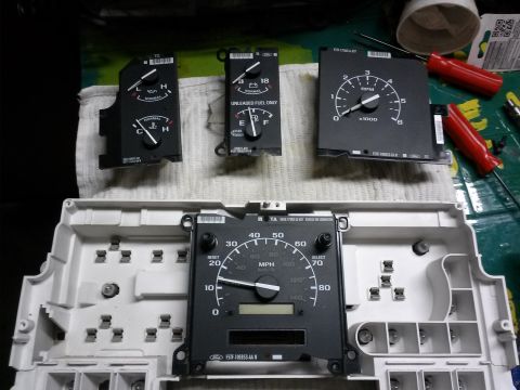 1996 Ford Bronco - Disassembled Ford Bronco instrument cluster parts laid out on a workbench.