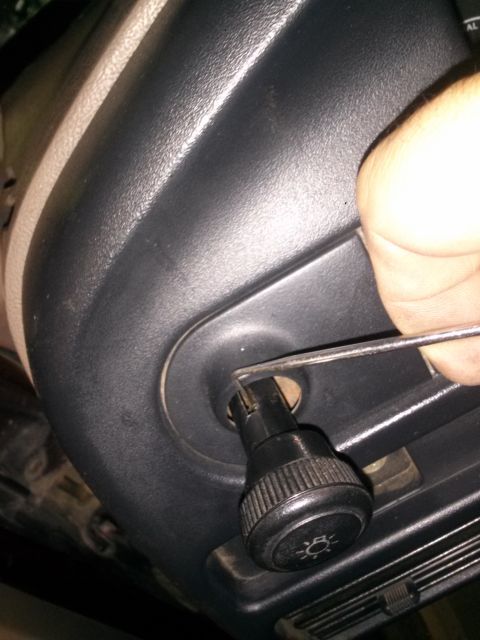 1996 Ford Bronco - Close-up of a hand adjusting a dashboard knob with a tool.