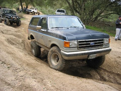 1989 Ford Bronco - This 1989 Ford Bronco navigates a challenging dirt path alongside other off-road vehicles.