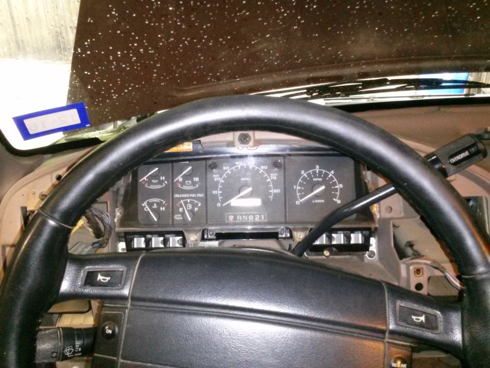 Dashboard gauges and steering wheel of a vehicle. The odometer reads RN021