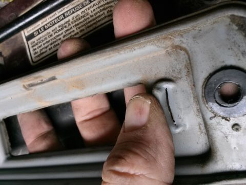 1996 Ford Bronco - A hand is shown operating a lever on a metal component, with a French warning label visible in the background.